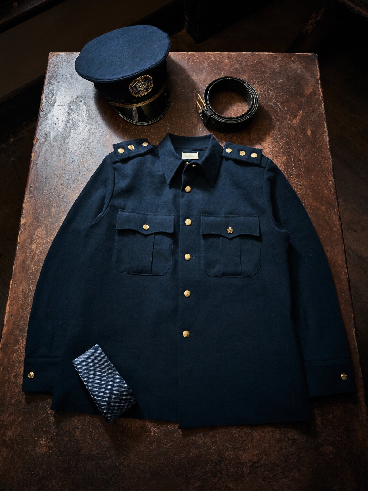 A folded navy uniform shirt resting on a worn wooden showroom table, lit by north-facing window light
