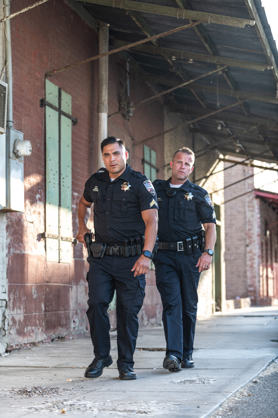 Two officers in daily duty uniforms walking a city sidewalk