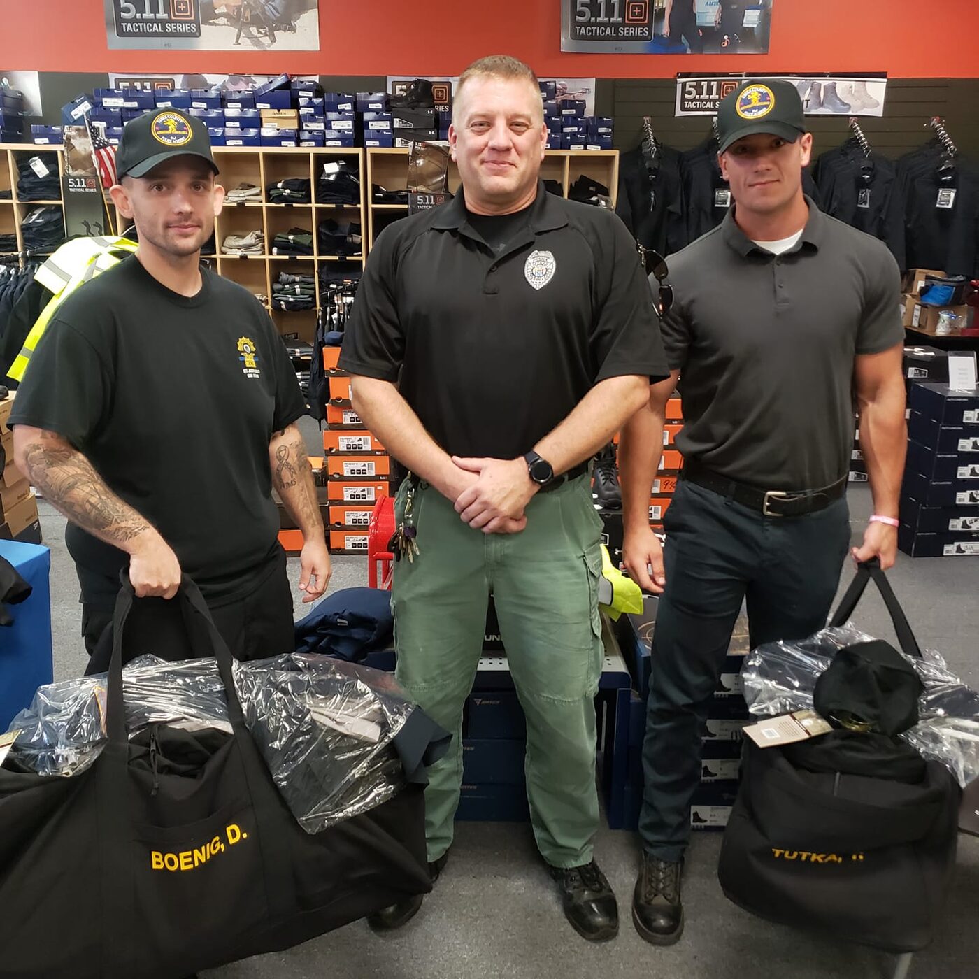 Three police academy recruits with their gear bags on the Atlantic Uniform sales floor