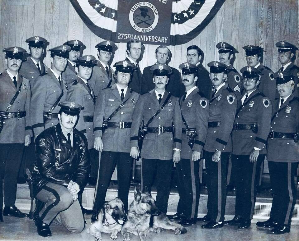 Vintage black and white photograph of police officers in formal dress uniforms standing in formation with a K9 unit